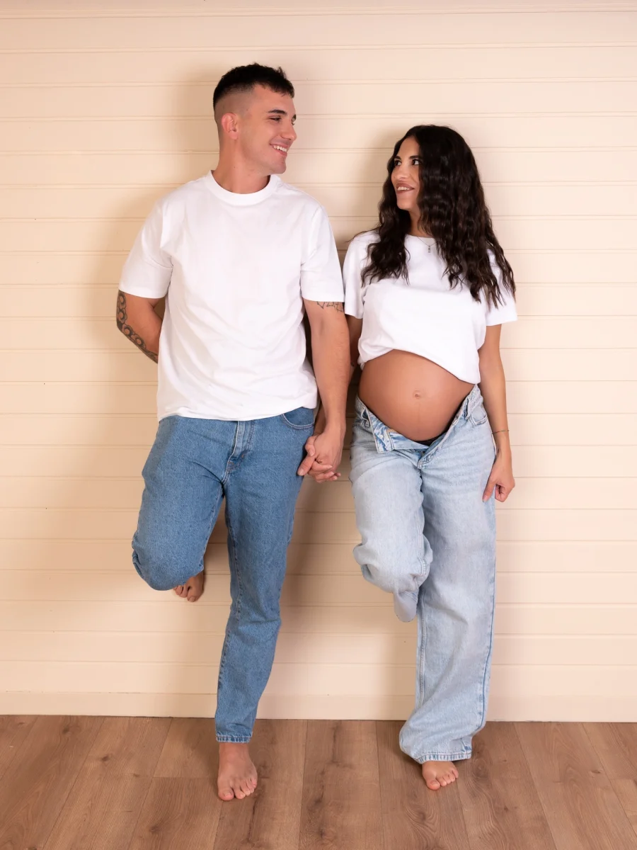 fotografía de una mujer embarazada y su pareja masculina apoyada sobre una pared